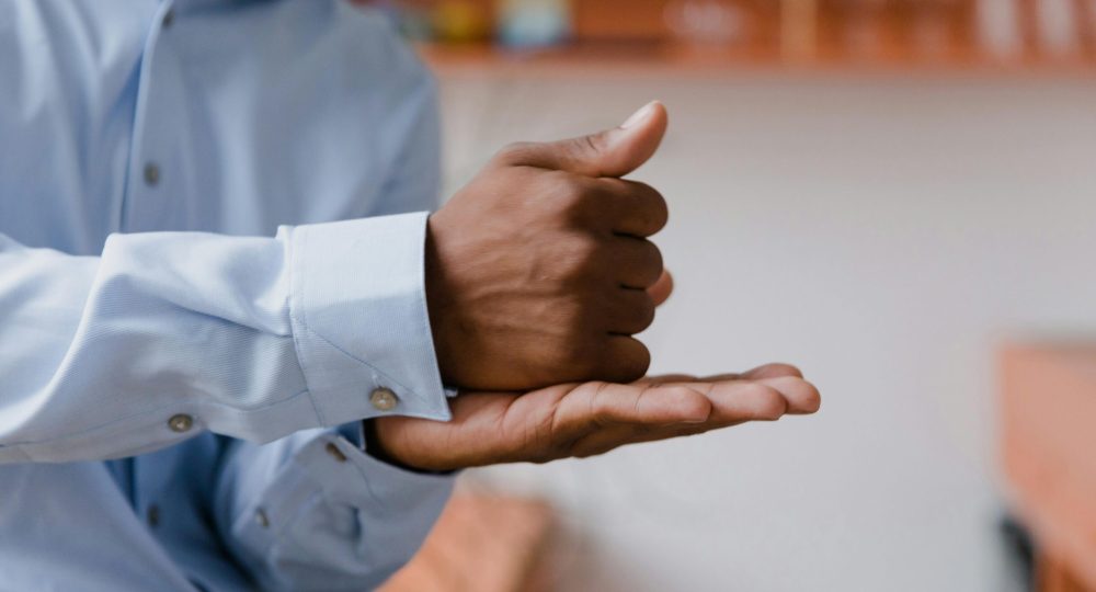 A man using sign language indoors with a focus on hand gestures and communication.